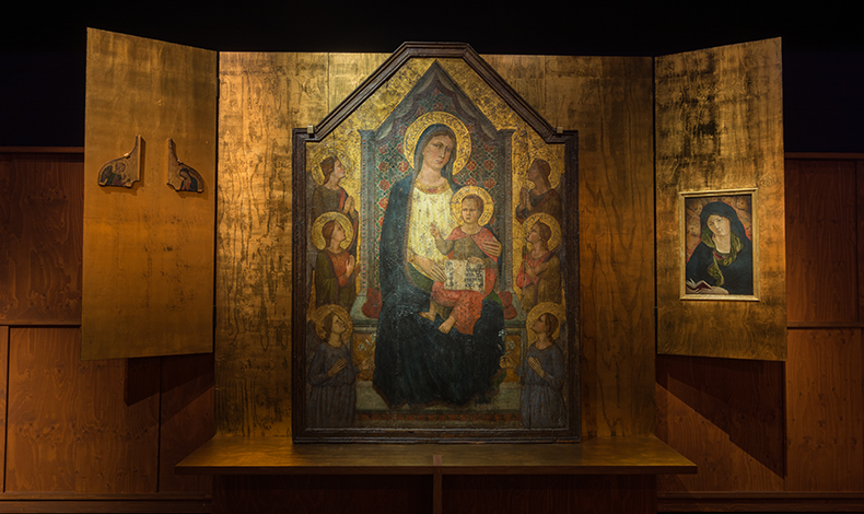 Kuvassa on Joensuun taidemuseon Madonna-näyttelyhuoneessa oleva alttariasetelmaa muistuttava seinä. Keskellä on suuri 1300-luvun Italiasta peräisin oleva alttaritaulu, joka esittää Neitsyt Mariaa ja Jeesus-lasta. Punavaatteinen Jeesus istuu tummansiniseen vaatteeseen pukeutuneen Maria sylissä, ja molemmilla on kullatut sädekehät. Kaksikkoa ympäröi molemmin puolin kolme enkeliä, joiden kädet ovat rukoilevassa asennossa. Myös enkeleillä on sädekehät. Alttaritaulua reunustaa molemmin puolin avautuvat puuseinäkkeet, joista vasemmanpuoleisessa on pienet siipiä muistuttavat esineet, ja oikeanpuolimmaisessa pienempi maalaus, joka esittää lukevaa Neitsyt Mariaa.